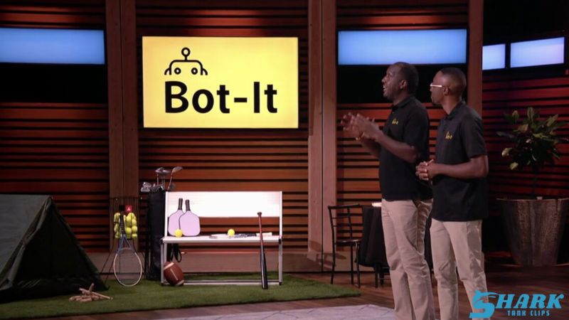 Shark Tank update on BOT-IT, Season 15 Episode 03, featuring two entrepreneurs pitching on stage with the BOT-IT logo in background
